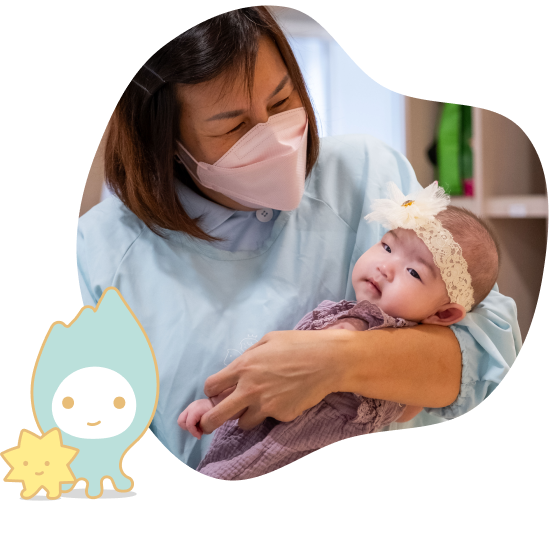 An Infant Teacher in uniform cradling a baby in the crook of one arm.