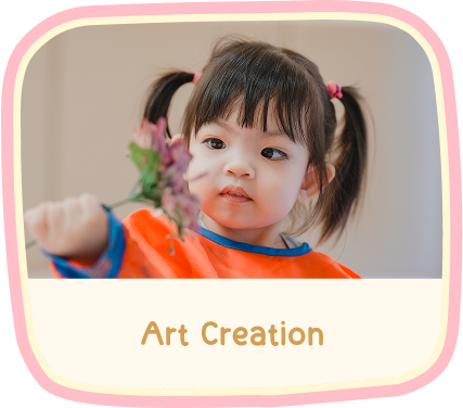 Art Creation — a toddler in an orange smock holding a small posy of flowers.